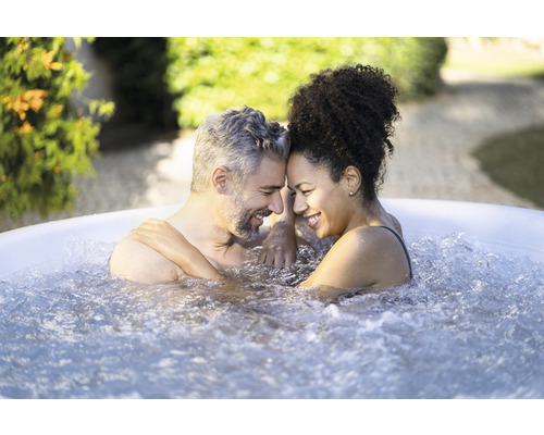 Een stel ontspant in een bubbelbad in de tuin.