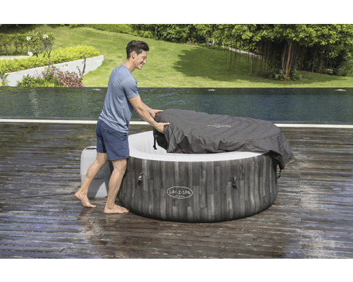 Persoon bedekt Lay-Z-Spa bubbelbad met afdekking in de tuin