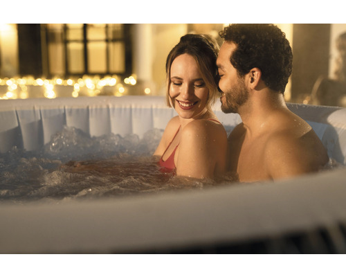 Een stel ontspant in een opblaasbare jacuzzi met warm water en bubbels buiten.