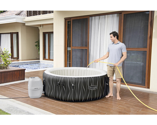 Persoon vult bubbelbad met waterslang in de tuin.