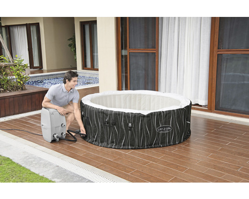 Man vult een opblaasbare Lay-Z-Spa whirlpool op een terras met een pomp.