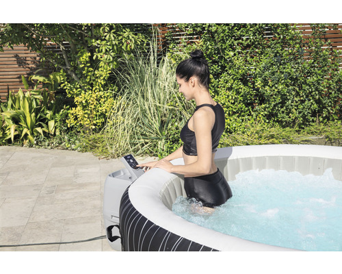 Vrouw in opblaasbare jacuzzi met bedieningspaneel in de tuin.