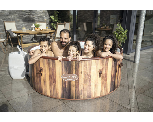 Familie ontspant in een Lay-Z-Spa Helsinki bubbelbad in de tuin.