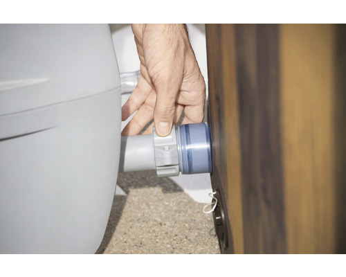 Een man sluit een grijze slang aan op een zwembad.