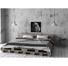 Slaapkamer met bed van pallets, lamp en leeuwenfoto