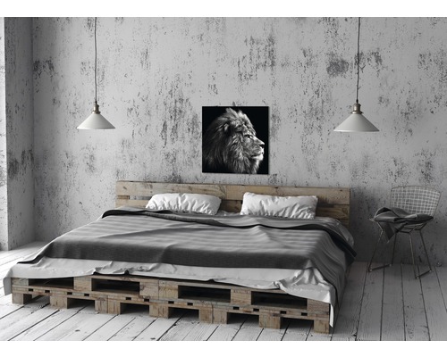 Slaapkamer met bed van pallets, lamp en leeuwenfoto