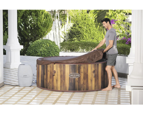 Man opent een deksel van een Lay-Z-Spa bubbelbad met houtlook in de tuin.