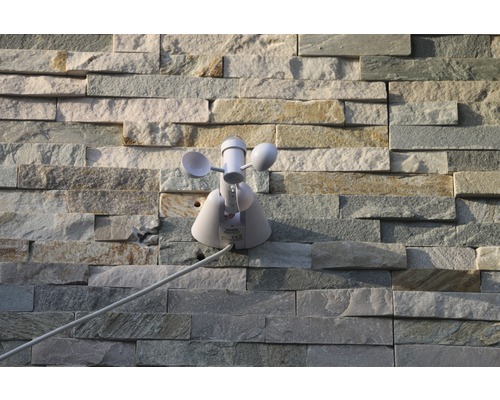 Weerstation met windmeter op stenen muur