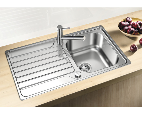 Roestvrijstalen spoelbak met afdruiprek en kraan op een werkblad.