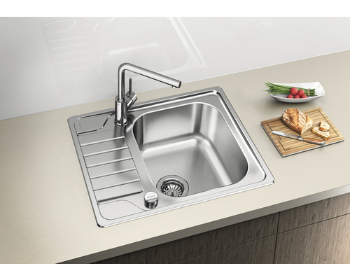 Roestvrijstalen spoelbak met afdruiprek en keukenkraan op een aanrecht met etenswaren