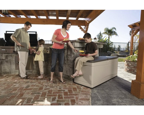 Gezin dat aan het barbecueën is in de tuin met een opbergbox als zitplaats