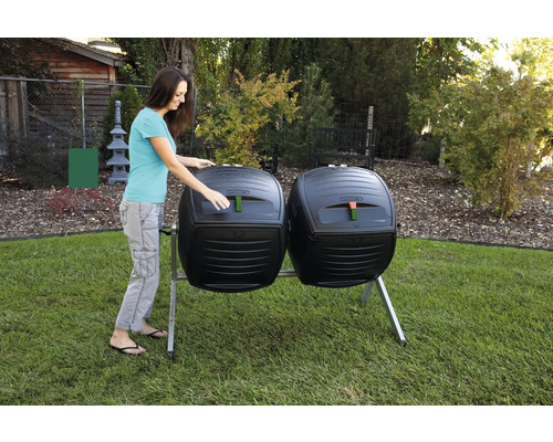 Twee composttrommels met een vrouw die een van de trommels opent, in de tuin.