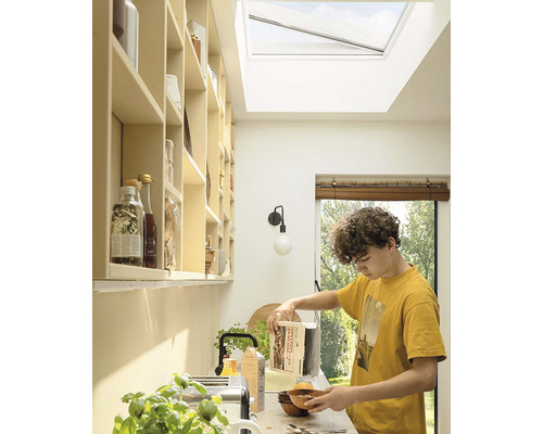 Lichte keuken met dakraam, schappen en een persoon die ontbijt maakt