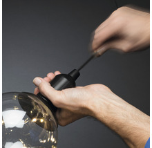 Een persoon bevestigt een lamp aan een ophangsysteem.