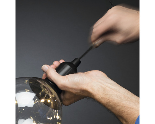 Een persoon bevestigt een lamp aan een ophangsysteem.