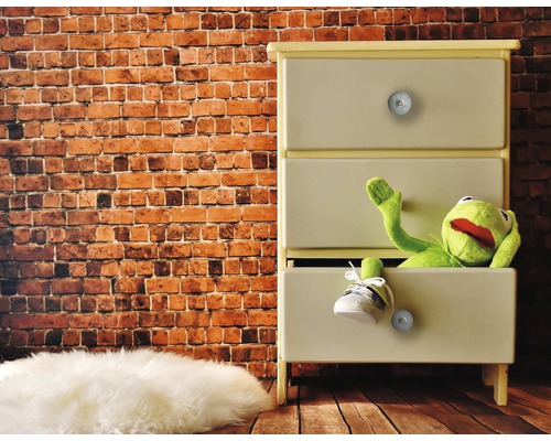 Dressoir met drie lades, een stoffen pop en een schoen voor een bakstenen muur