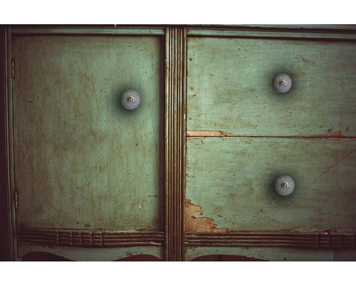 Detailopname van een groene houten kast met drie laden en ronde handgrepen