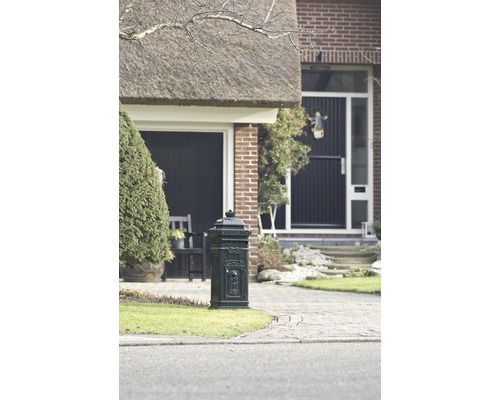 Decoratieve metalen brievenbusinstallatie voor een huis met rieten dak.