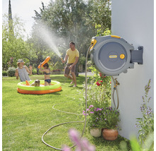 Familie gebruikt een automatische tuinslangbox van Hozelock om te sproeien en te spelen in de tuin.