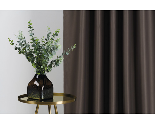 Decoratieve opstelling met gordijn, tafel en vaas met groene planten