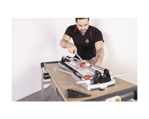 Man bedient tegelsnijder van het merk Rubi op een werktafel.