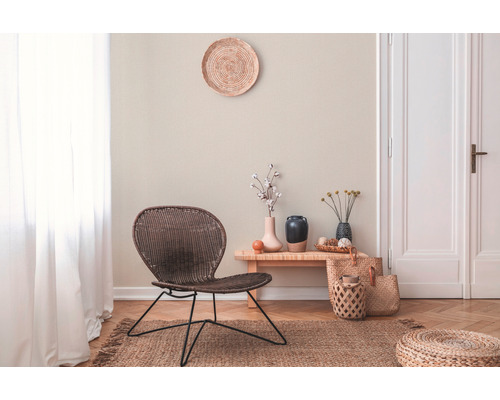 Woonkamer met rotan stoel, houten bijzettafel, decoratie en vloerkleed