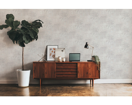 Woonkamer met behang met patroon, houten dressoir, kamerplant en bureaulamp