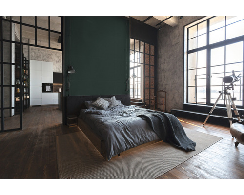 Loftstijl slaapkamer met bed, vloerkleed en ramen