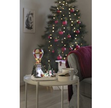 Decoratief kerstlandschap met luchtballon op een tafel naast een kerstboom.