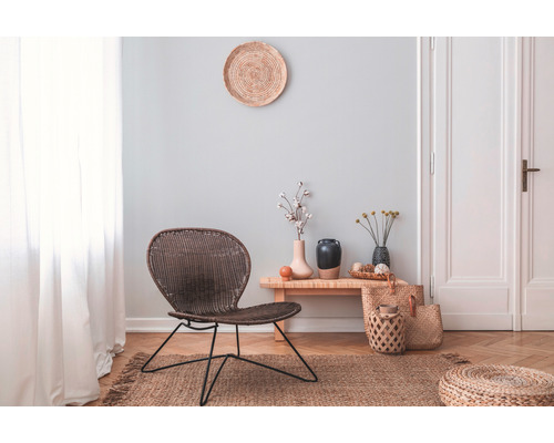 Woonkamer met rotan stoel, houten bijzettafel en decoratie