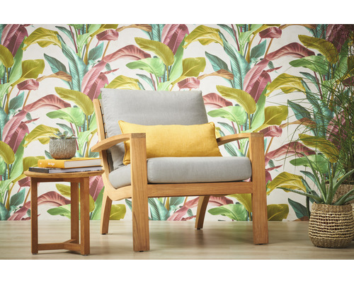 Tuinscene met fauteuil, kussens en bijzettafel tegen een achtergrond van patroonbehang