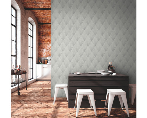 Woonkamer met patroonbehang, houten vloer en eettafel met stoelen.