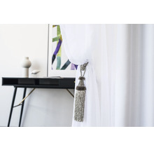 Decoratieve gordijnkwast aan een wit gordijn, op de achtergrond een bureau met decoratie