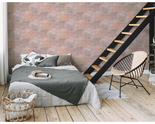 Slaapkamer met bed, ladder, rotan stoel en patroonbehang voor een gezellige sfeer