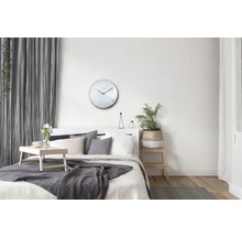 Lichte slaapkamer met bed, tafel, plant en ronde wandklok