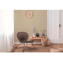 Woonkamer met beige textielbehang, rotan stoel en decoraties voor een natuurlijke sfeer.