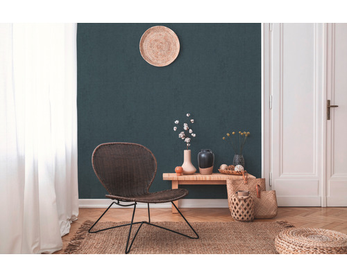 Woonkamer met rotan stoel, houten tafel, vazen, jute tapijt en decoratie voor een donkergroene muur