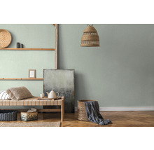 Woonkamer met groen textielbehang, houten plank en gevlochten mand