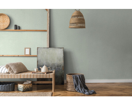 Woonkamer met groen textielbehang, houten plank en gevlochten mand