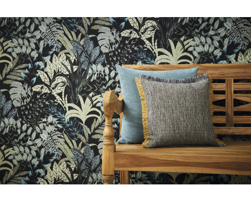 Decoratieve kussens op een houten bank voor een muur met bladpatroonbehang.