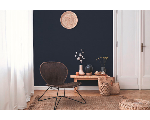 Woonkamer met gevlochten stoel, houten bijzettafel en decoratieve accessoires op een vloerkleed