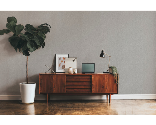 Woonkamer met grijs structuurbehang, houten dressoir, kamerplant en bureaulamp.