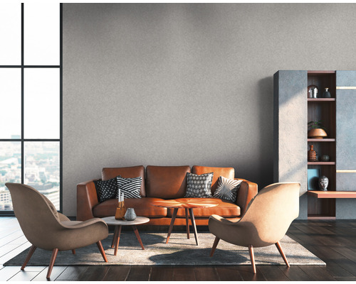 Woonkamer met bruine leren bank, twee fauteuils, salontafels en rek