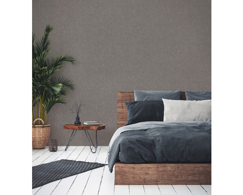 Slaapkamer met houten bed, nachtkastje, kamerplant en vloerkleed op een houten vloer.