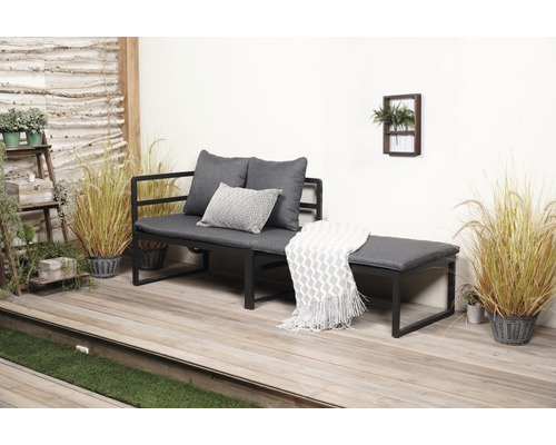 Tuinbank met grijze kussens en decoratieve deken op een terras