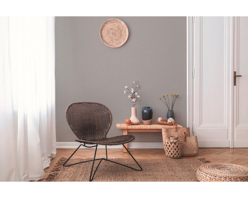 Lichte woonkamer met rotan stoel, houten bijzettafel en diverse decoratieve elementen.