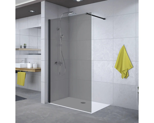 Inloopdouche met getint glaspaneel, zwarte stabilisatiestang en doucheset in een moderne badkamer met grijze tegels.