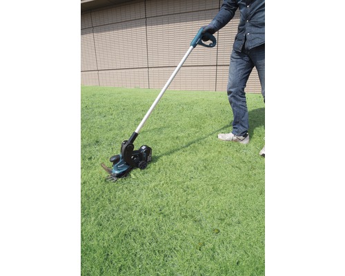 Persoon gebruikt accukantensnijder in de tuin.