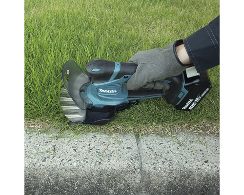 Makita kantensnijder in gebruik voor het snijden van gras langs een betonnen rand