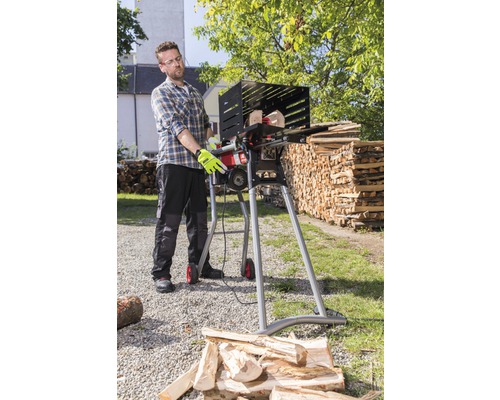 Een man bedient een brandhoutzaag om buiten hout te zagen.